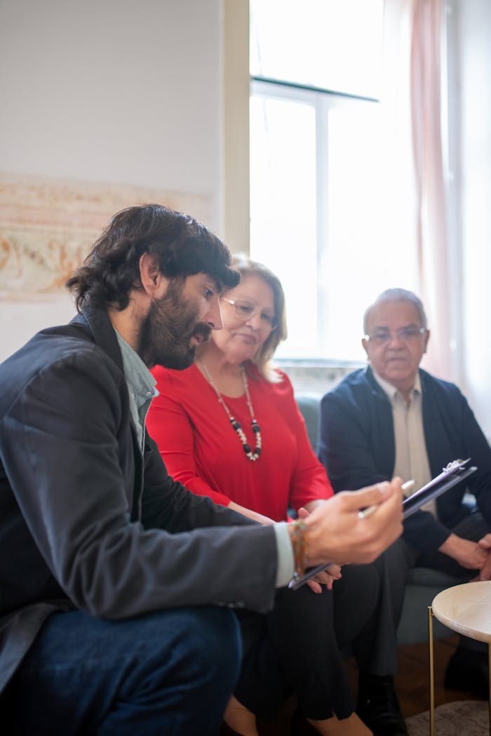 hero-img-01 Consulting agent discussing documents with senior couple indoors during a business meeting.